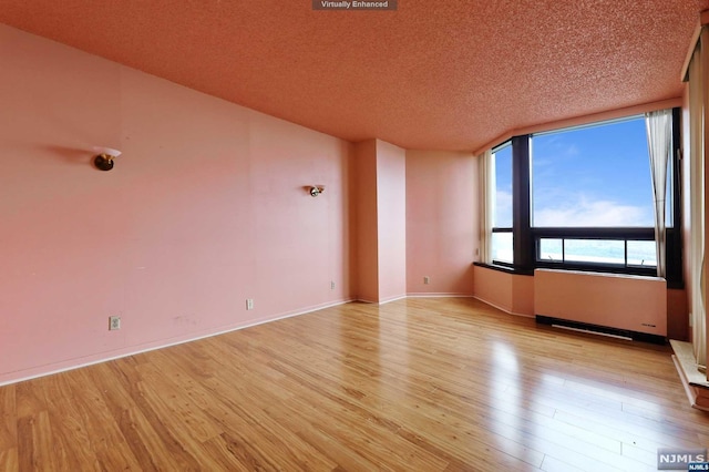 unfurnished room featuring radiator, light hardwood / wood-style flooring, and a textured ceiling