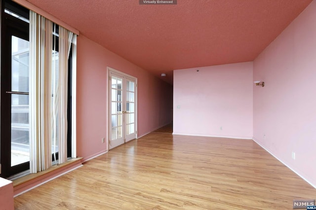 unfurnished room featuring french doors, a textured ceiling, and light hardwood / wood-style floors