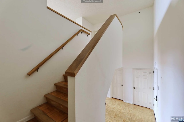 stairs featuring a textured ceiling and parquet flooring