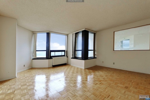 spare room with a textured ceiling, radiator, and light parquet floors