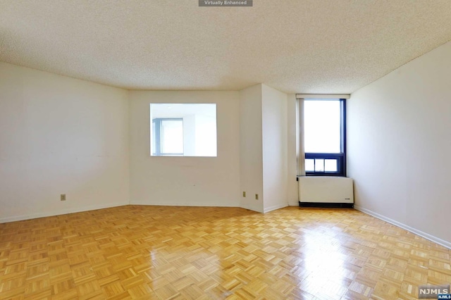 bonus room featuring radiator heating unit, a textured ceiling, and light parquet floors