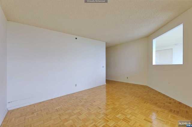 empty room with a textured ceiling and light parquet flooring