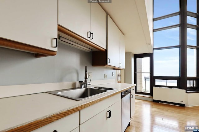 kitchen with dishwasher, radiator, sink, light hardwood / wood-style floors, and white cabinetry