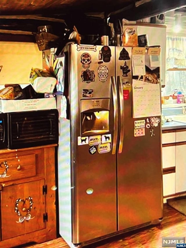 interior details featuring stainless steel fridge with ice dispenser and light hardwood / wood-style flooring