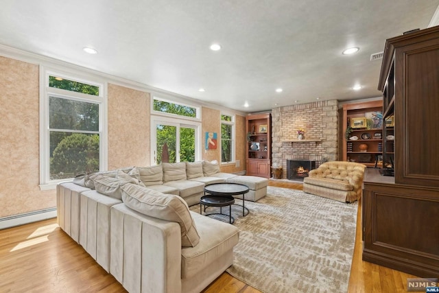 living room featuring a fireplace, light wood-type flooring, a baseboard radiator, and ornamental molding