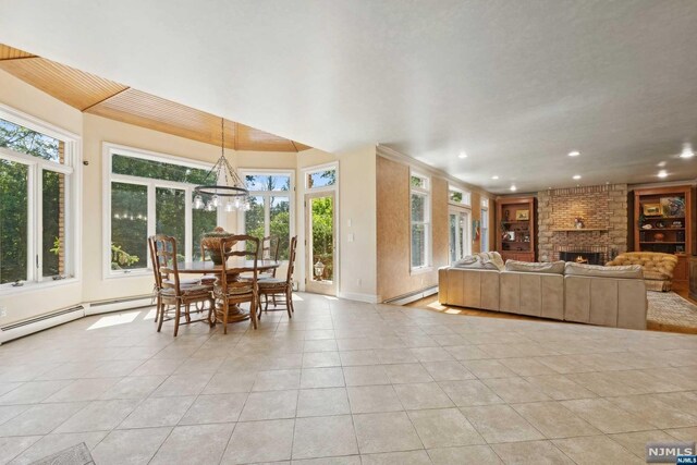 living room featuring light tile patterned flooring, an inviting chandelier, a fireplace, and a baseboard radiator