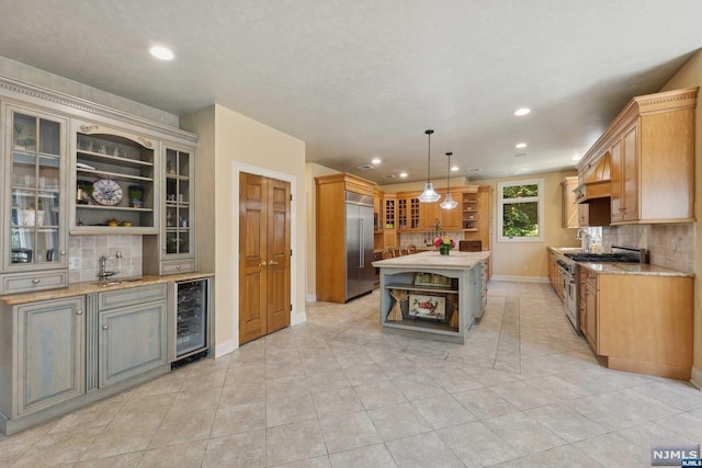 kitchen with beverage cooler, backsplash, pendant lighting, high quality appliances, and a kitchen island