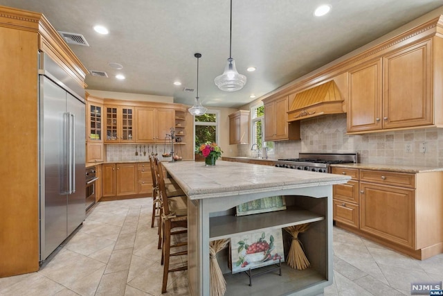 kitchen featuring hanging light fixtures, tasteful backsplash, a kitchen island, custom range hood, and appliances with stainless steel finishes