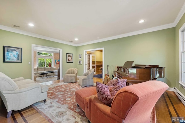 living room with ornamental molding, a baseboard radiator, and light wood-type flooring