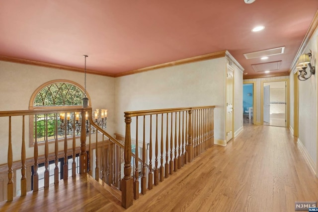 hall featuring light wood-type flooring, ornamental molding, and a chandelier