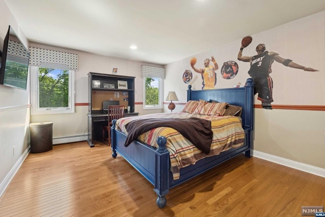 bedroom featuring hardwood / wood-style flooring and a baseboard heating unit