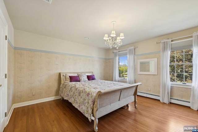 bedroom featuring a chandelier, hardwood / wood-style flooring, and baseboard heating