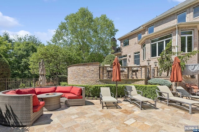 view of patio with an outdoor living space with a fire pit