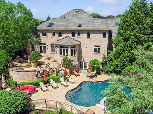 rear view of property with a patio and a fenced in pool