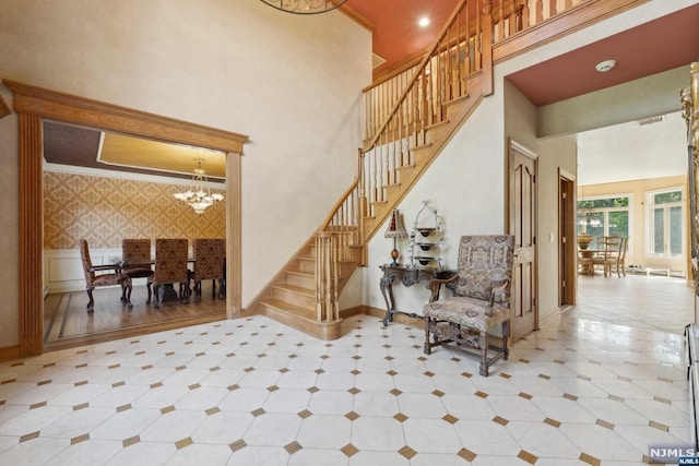 stairs featuring a towering ceiling, an inviting chandelier, and crown molding