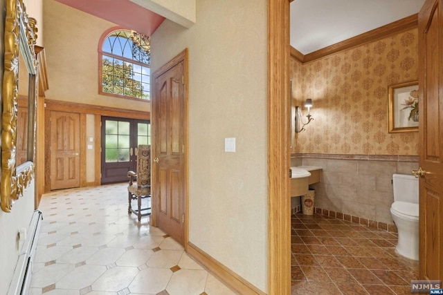 entrance foyer with a baseboard heating unit and crown molding