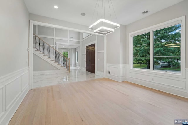 interior space with light hardwood / wood-style flooring, built in features, and an inviting chandelier