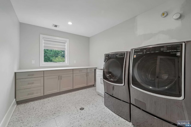 laundry room featuring washing machine and clothes dryer and cabinets