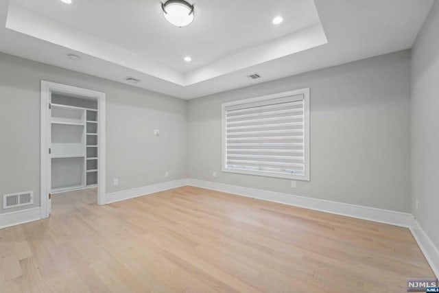 unfurnished room with a tray ceiling and light hardwood / wood-style flooring