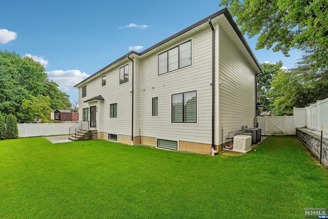 back of property featuring central AC and a lawn