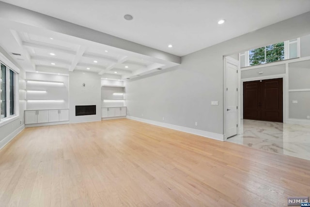 unfurnished living room with beam ceiling, light hardwood / wood-style flooring, and coffered ceiling