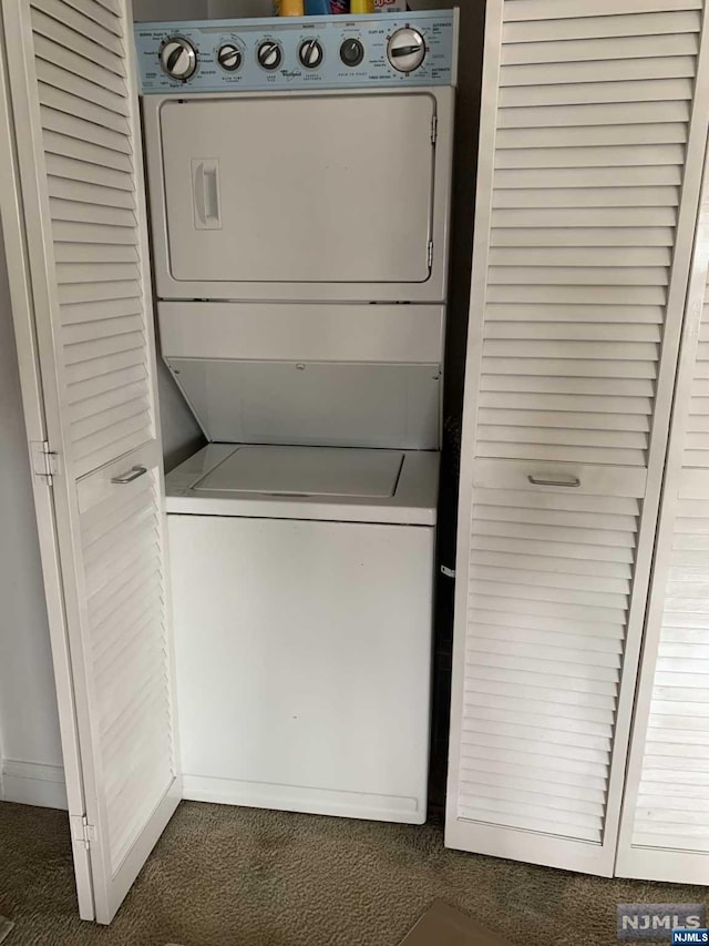 clothes washing area with stacked washer and dryer and dark carpet