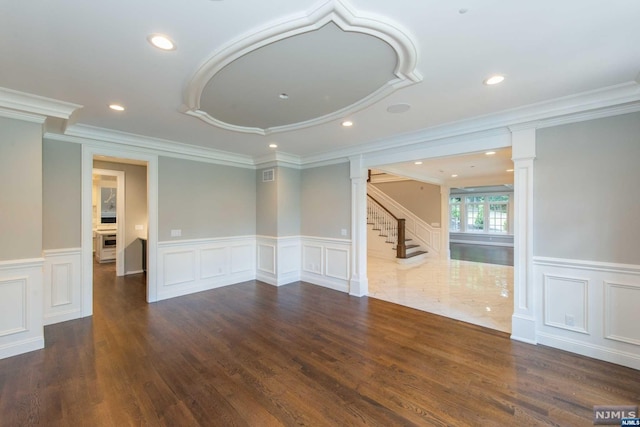 spare room featuring dark hardwood / wood-style floors, ornamental molding, and ornate columns