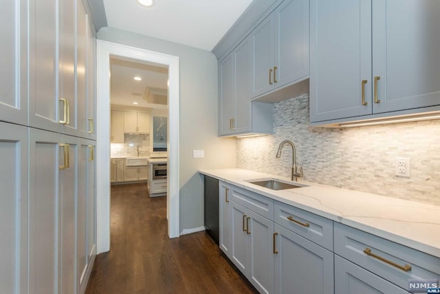 kitchen with dark hardwood / wood-style floors, decorative backsplash, light stone counters, and sink