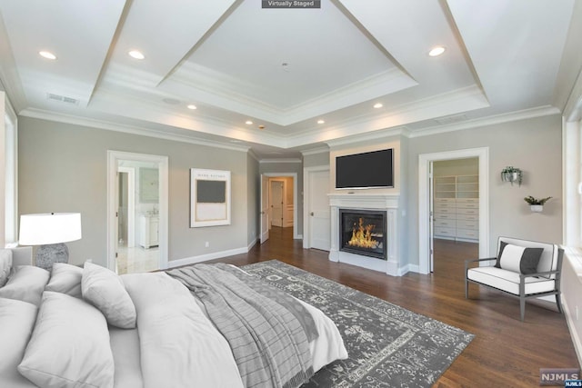 bedroom featuring ensuite bathroom, dark hardwood / wood-style flooring, crown molding, and a raised ceiling