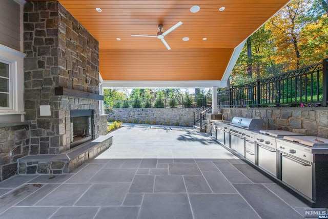 view of patio / terrace featuring ceiling fan, a grill, an outdoor stone fireplace, and area for grilling