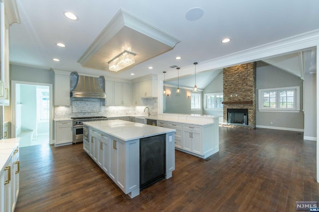 kitchen with wall chimney exhaust hood, decorative light fixtures, white cabinetry, kitchen peninsula, and high end stainless steel range oven