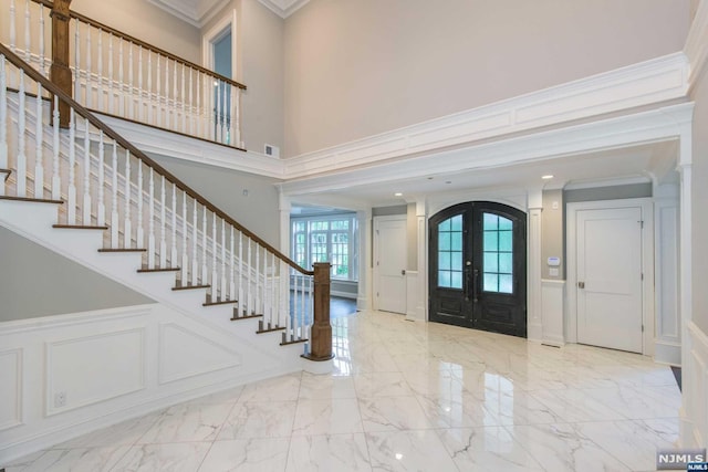 foyer entrance featuring a high ceiling, ornamental molding, and french doors