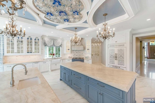 kitchen with white cabinetry, sink, premium range hood, a large island, and blue cabinets