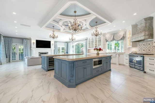 kitchen with double oven range, white cabinetry, a raised ceiling, custom range hood, and a center island