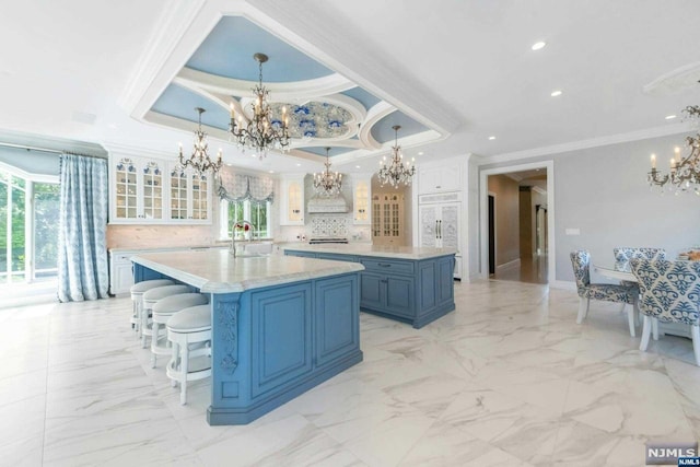 kitchen featuring ornamental molding, a tray ceiling, hanging light fixtures, and a large island