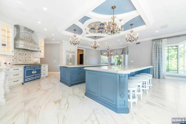 kitchen with white cabinetry, custom exhaust hood, a large island, decorative light fixtures, and blue cabinets