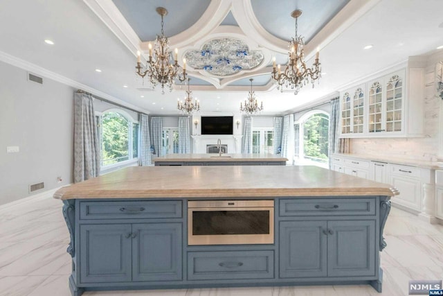 kitchen with white cabinetry, crown molding, a raised ceiling, and a center island