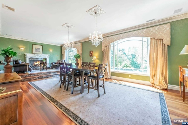 dining area featuring ornamental molding, a notable chandelier, and light wood-type flooring