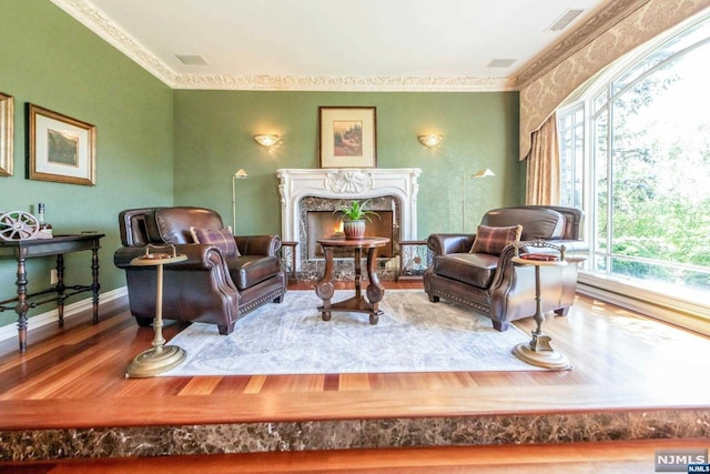 sitting room featuring a high end fireplace, crown molding, and hardwood / wood-style flooring