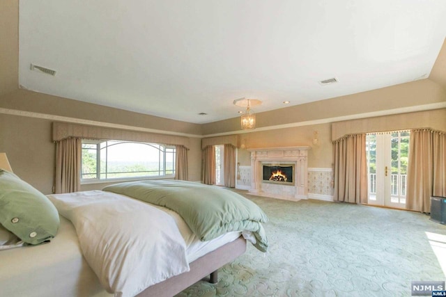 bedroom featuring access to exterior, light colored carpet, and a high end fireplace