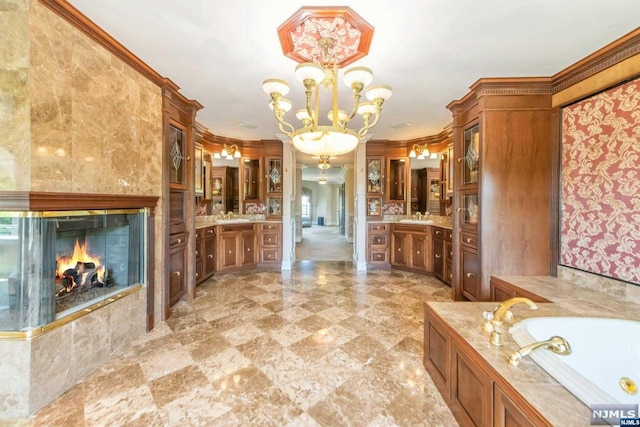 bathroom with an inviting chandelier, crown molding, a fireplace, and vanity