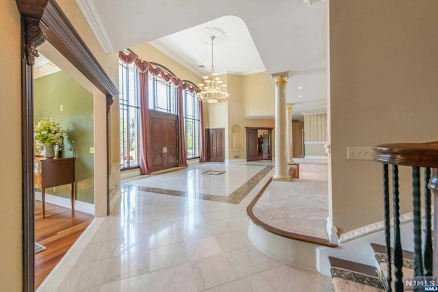 foyer with ornamental molding, ornate columns, a notable chandelier, and light tile patterned flooring