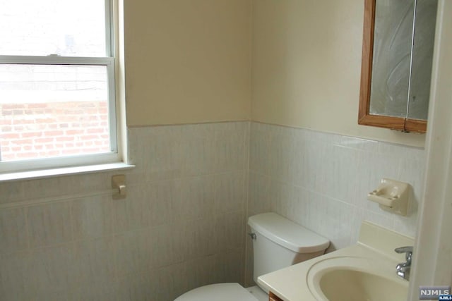 bathroom featuring vanity, toilet, and tile walls