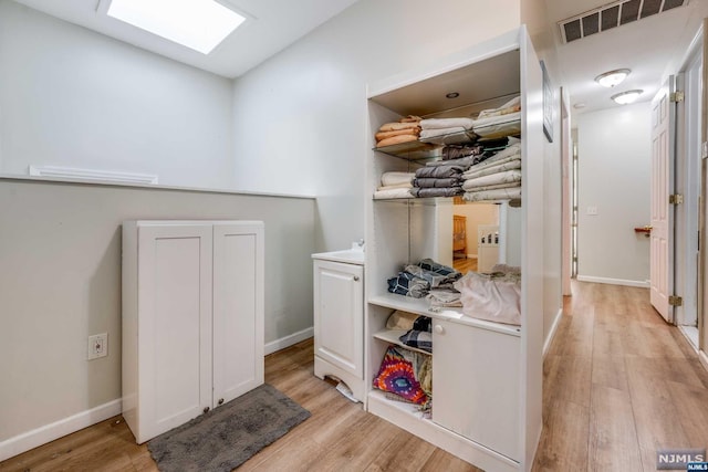 corridor with light hardwood / wood-style floors and a skylight