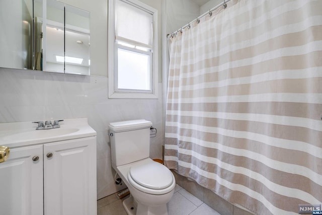 bathroom with tile patterned floors, vanity, tile walls, and toilet