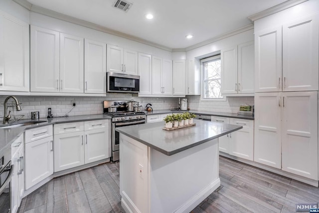 kitchen with appliances with stainless steel finishes, light hardwood / wood-style flooring, and white cabinetry