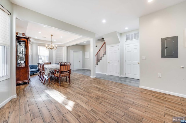 dining room with electric panel, a chandelier, and light wood-type flooring