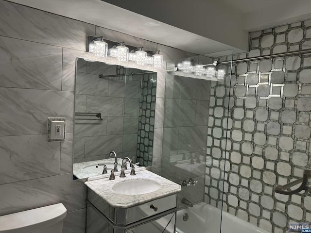 full bathroom featuring vanity, toilet, tile walls, and tiled shower / bath combo