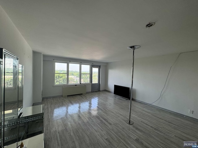 empty room featuring radiator heating unit and hardwood / wood-style floors