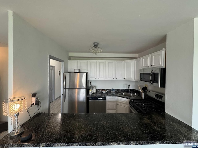 kitchen featuring kitchen peninsula, appliances with stainless steel finishes, white cabinetry, and sink